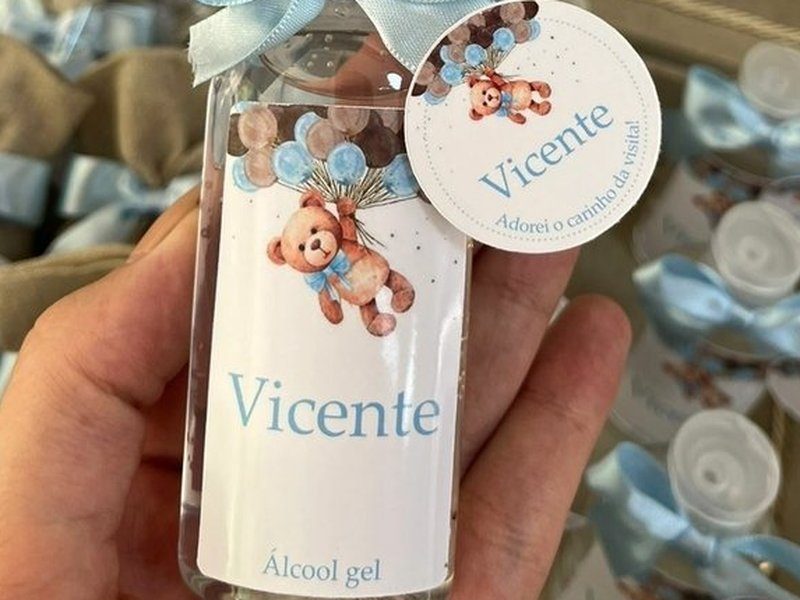 O r�tulo do �lcool gel com o ursinho segurando bal�es azuis e marrons, o nome Vicente e a indica��o �lcool gel