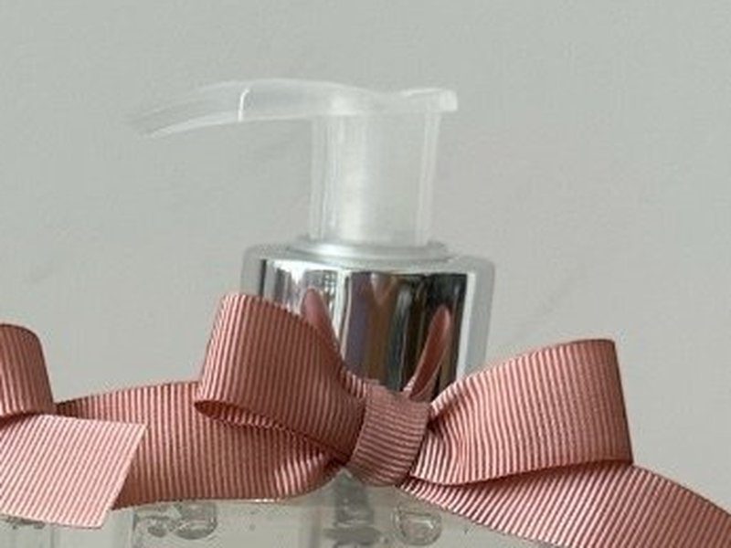 A v�lvula pump transparente do �lcool gel sobre o colarinho prateado do frasco de vidro