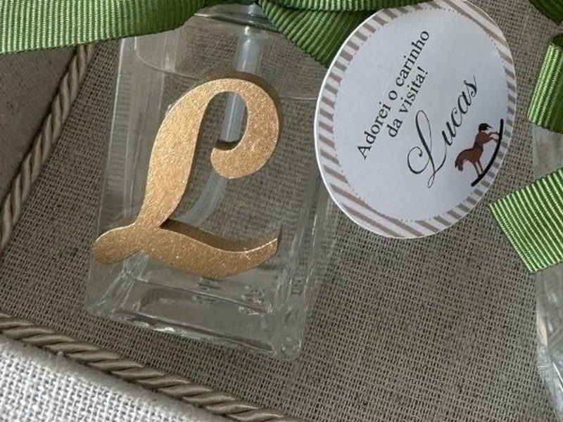 A letra L em relevo dourado no frasco de v�lvula spray dourada, com la�o de gorgur�o verde escuro
