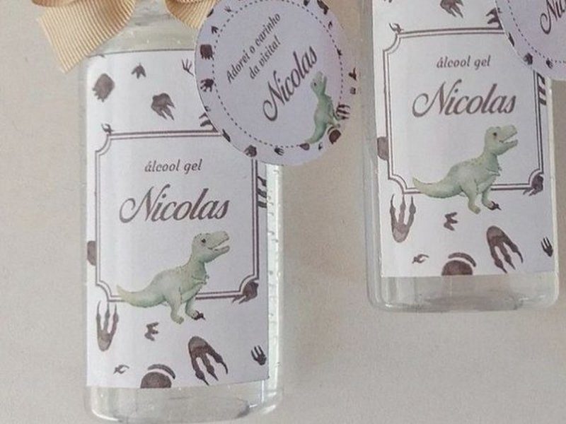 R�tulo tema dinossauro: moldura fina, o nome Nicolas em cursiva marrom, um T-rex verde-�gua e pegadas espalhadas pelo fundo