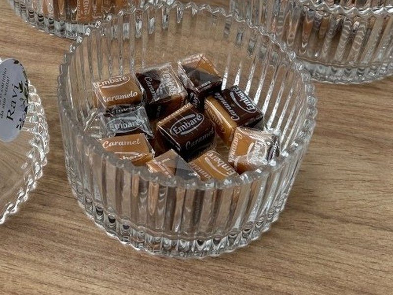O pote destampado com a tampa deitada ao lado, mostrando as balas de caramelo dentro