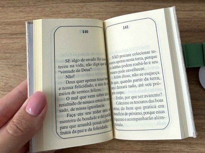 O livrinho aberto nas p�ginas 140 e 141, com texto corrido leg�vel