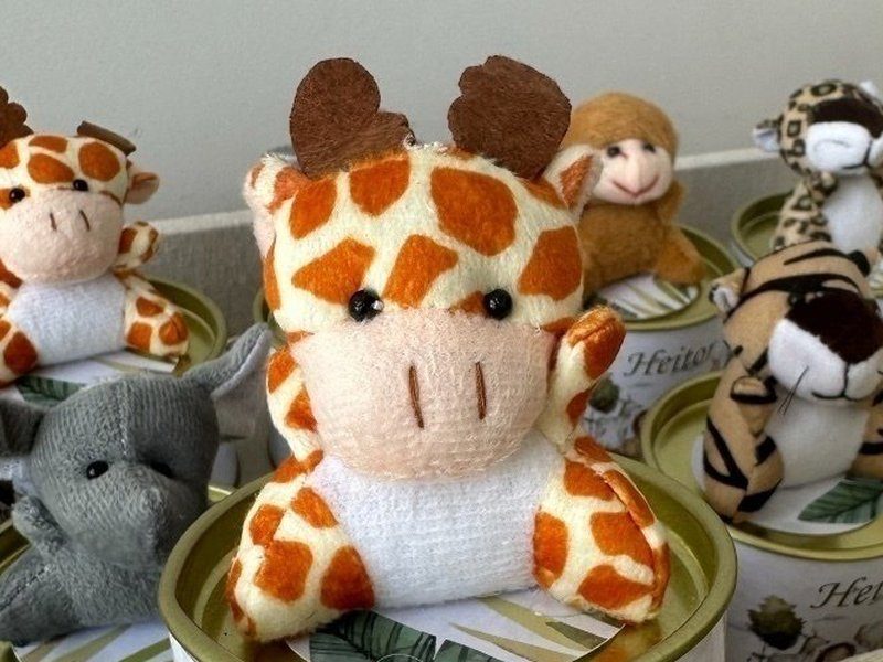 A girafa de pel�cia em close, com as manchas laranja, os chifres marrons e a camiseta branca