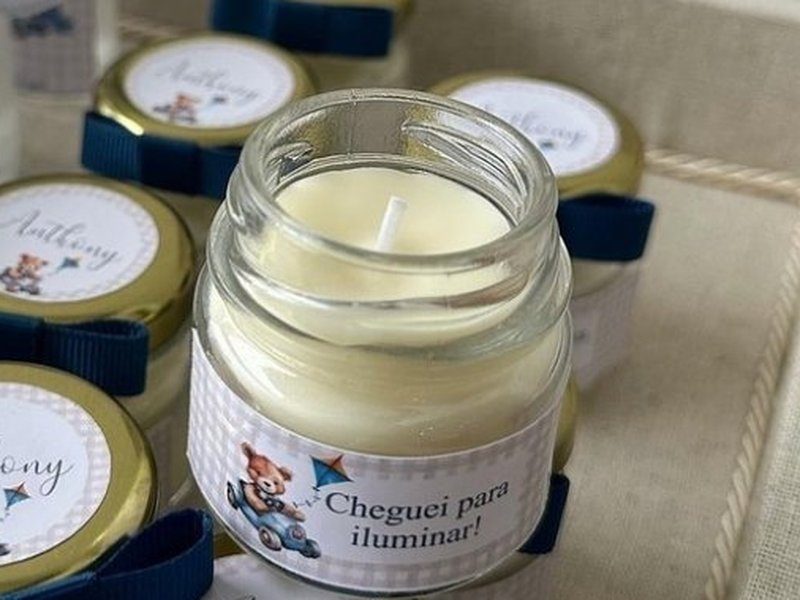 A vela aberta, de cera branca e pavio central, com a tampa met�lica dourada e o r�tulo Cheguei para iluminar!