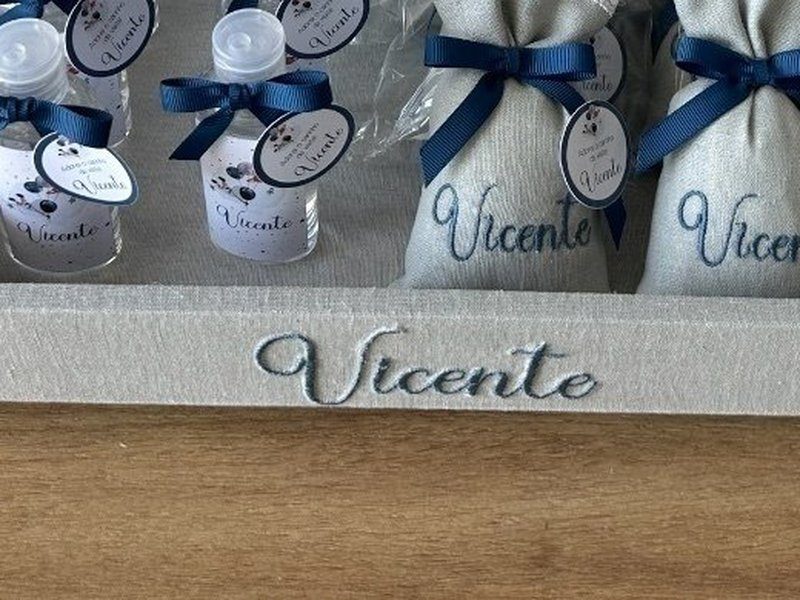 O nome Vicente bordado por inteiro em cursiva azul na lateral frontal da bandeja de linho