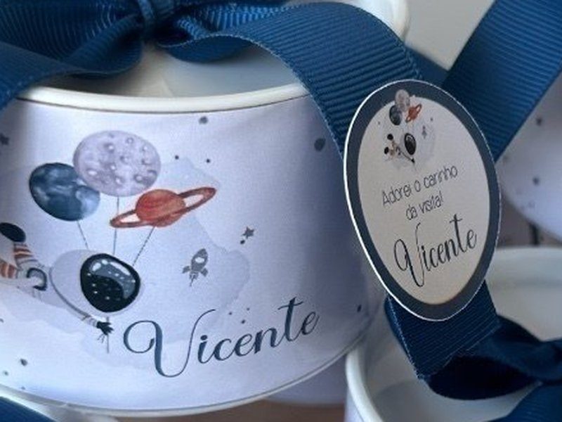 R�tulo da lata com astronauta, planetas e bal�o em aquarela e o nome Vicente em cursiva, sob o la�o de gorgur�o azul-petr�leo