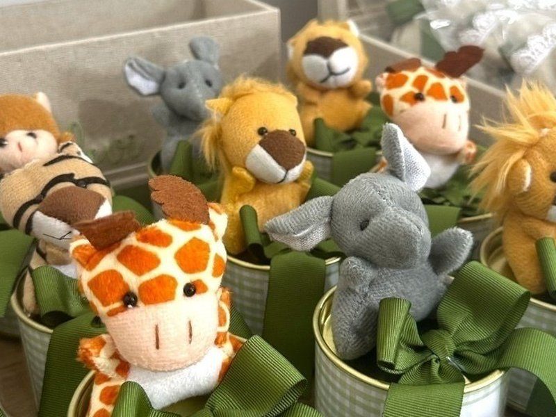 Latinhas xadrez verde com pel�cias distintas encaixadas: girafa, elefante, le�o e macaco, cada uma com la�o de gorgur�o verde