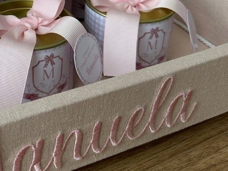 O nome Manuela bordado em rosa com relevo do ponto na lateral da bandeja