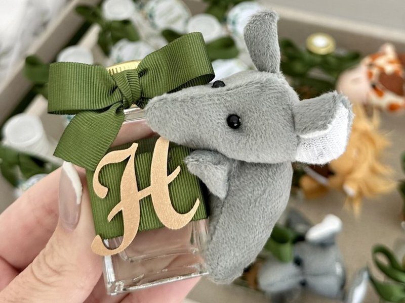 Frasco quadrado de vidro com faixa de gorgur�o verde escuro, a inicial H dourada inteira e um elefante de pel�cia cinza preso ao la�o