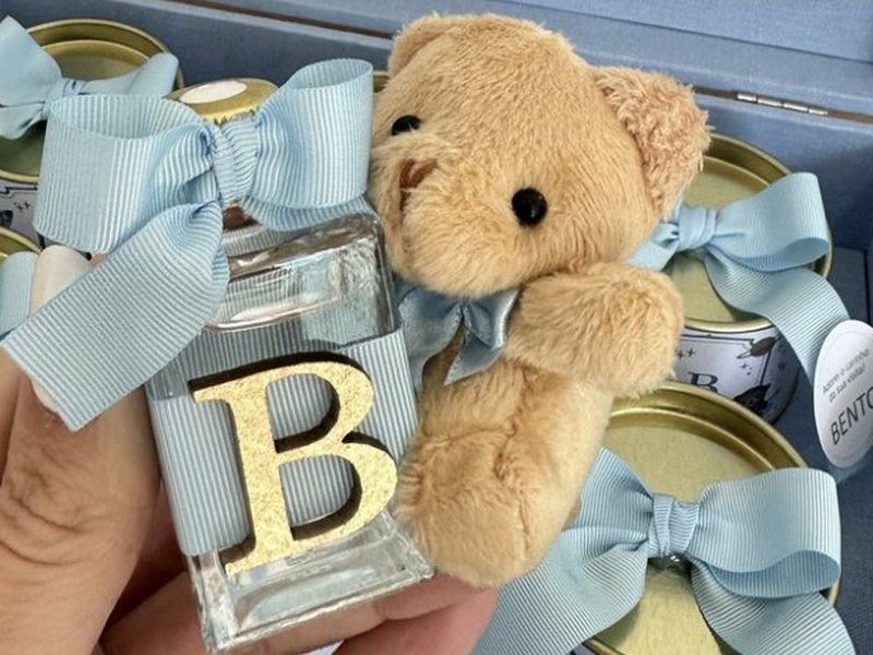 Aromatizador de vidro com faixa listrada azul, a inicial B dourada inteira e um urso de pel�cia com la�o azul