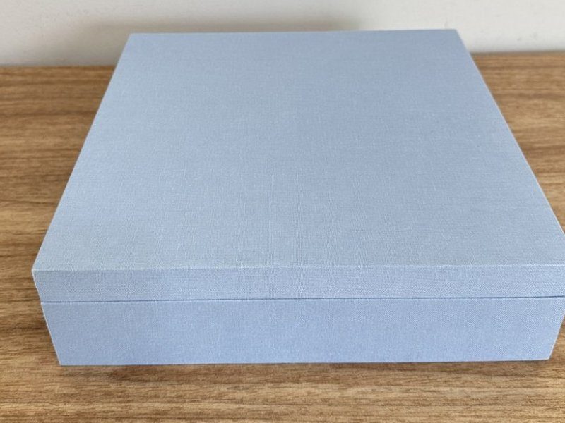 A caixa fechada vista de frente: revestimento azul liso, sem bordado na parte externa