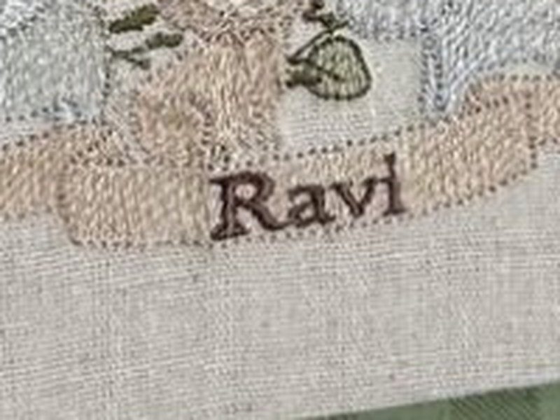 Faixa bege com o nome Ravi bordado por inteiro em marrom