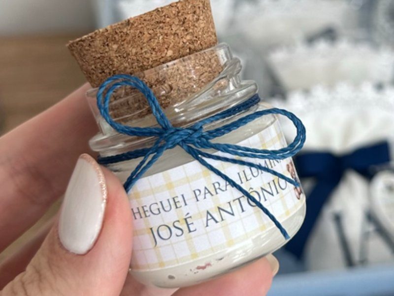 Pote de vidro com rolha de corti�a, la�o de barbante azul e r�tulo CHEGUEI PARA ILUMINAR com o nome