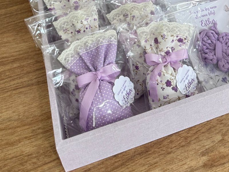 Sach�s em dois tecidos estampados diferentes, um de po� lil�s e outro floral roxo, ambos com renda branca e la�o lil�s