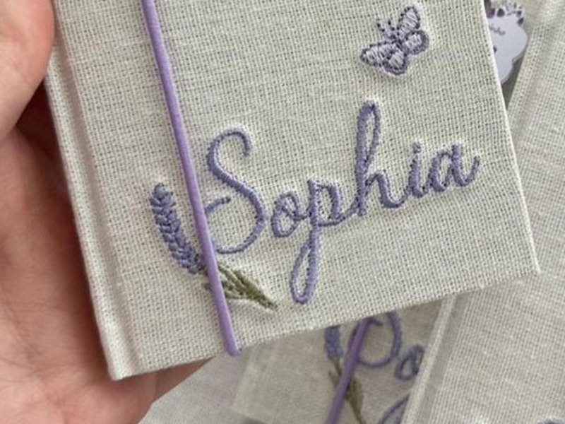 Nome Sophia bordado por inteiro em cursiva lil�s, com raminho de lavanda e uma borboleta