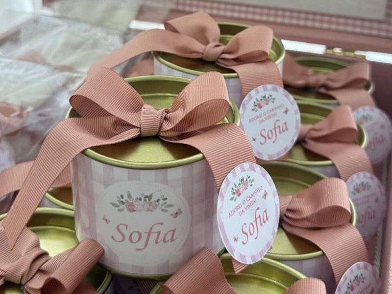 A lata de doces com r�tulo xadrez rosa, tampa dourada, la�o de gorgur�o amarrado em cruz e tag com o nome