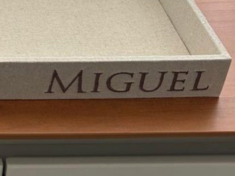 Nome MIGUEL bordado em mai�sculas serifadas na lateral direita da faixa da bandeja