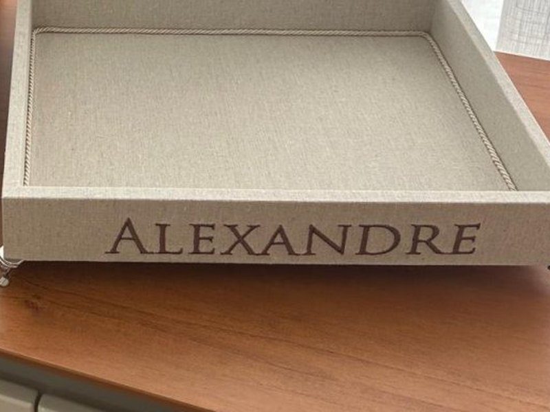 Nome ALEXANDRE bordado em mai�sculas na faixa frontal da bandeja, com p�s de metal � vista