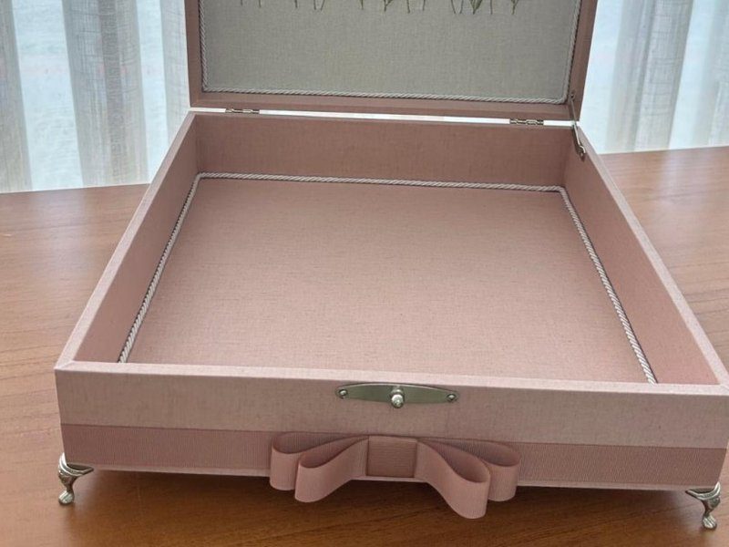 Fecho de metal prateado, p�s de metal e faixa de gorgur�o rosa com la�o na base da caixa