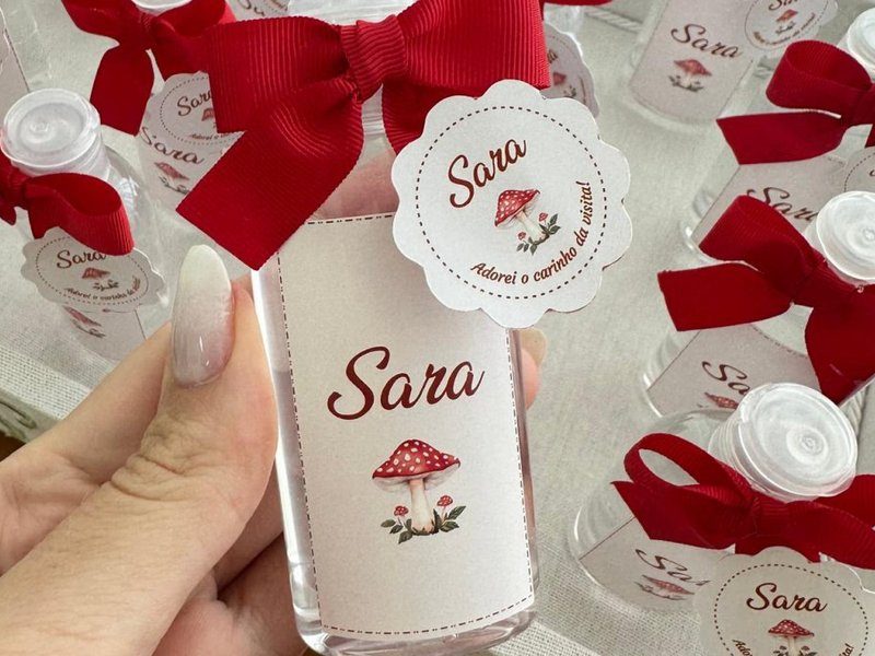 Frasco de �lcool gel com la�o vermelho, r�tulo Sara com cogumelo e tag redonda escalopada