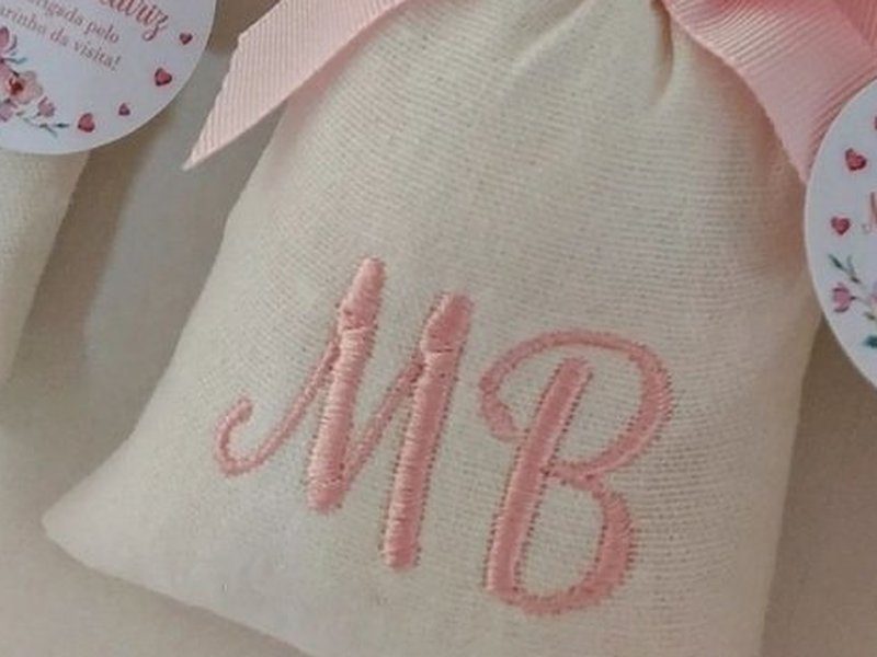 Sach� bordado apenas com as iniciais MB em cursiva rosa, em vez do nome inteiro