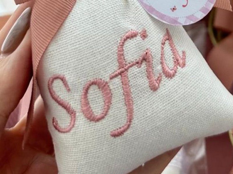 O nome Sofia bordado por inteiro em cursiva rosa sobre o tecido claro do sach�