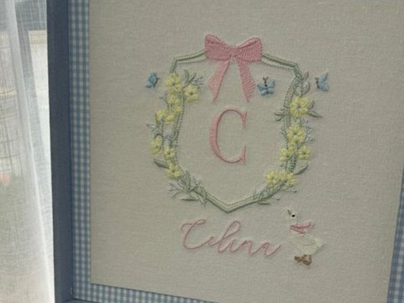 Escudo bordado com inicial C rosa, coroa de flores amarelas, la�o rosa, borboletas azuis, patinho e Celine em cursiva