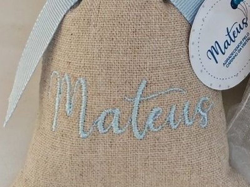 Mateus bordado em azul-claro em cursiva no linho do sach�, sob o la�o de gorgur�o azul