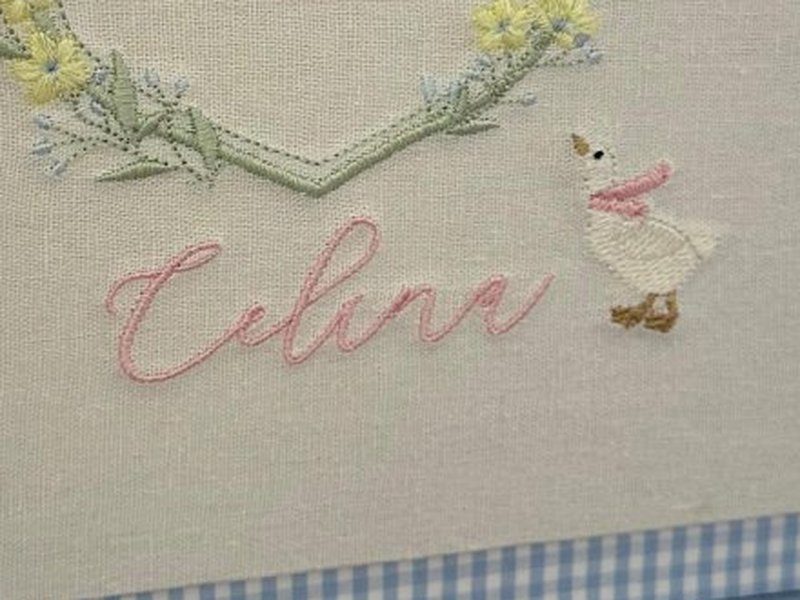 O nome Celina bordado por inteiro em cursiva rosa, com um ganso de len�o rosa bordado ao lado