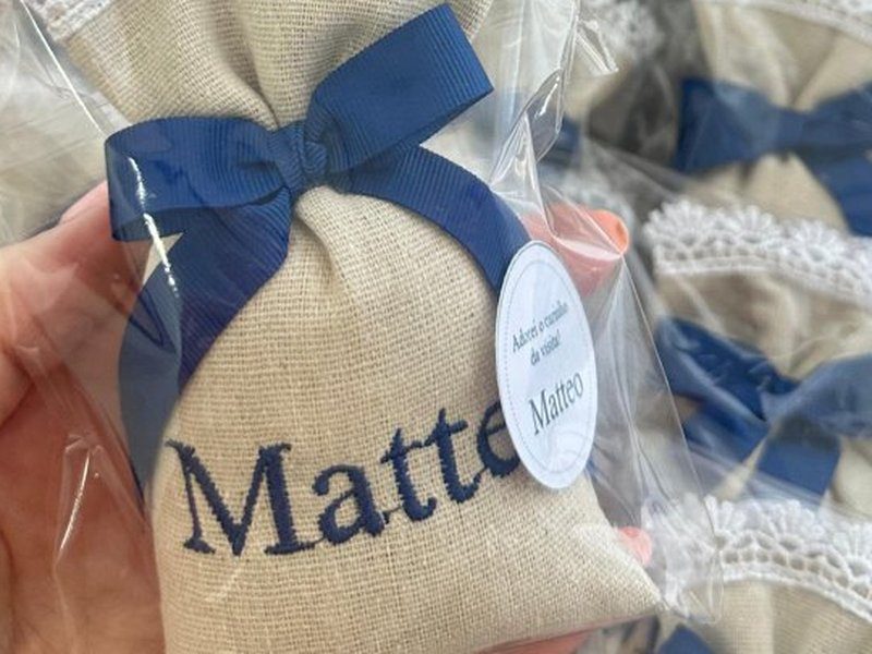 Saquinho de linho com bico de renda branca, la�o azul escuro e o nome Matteo bordado por inteiro