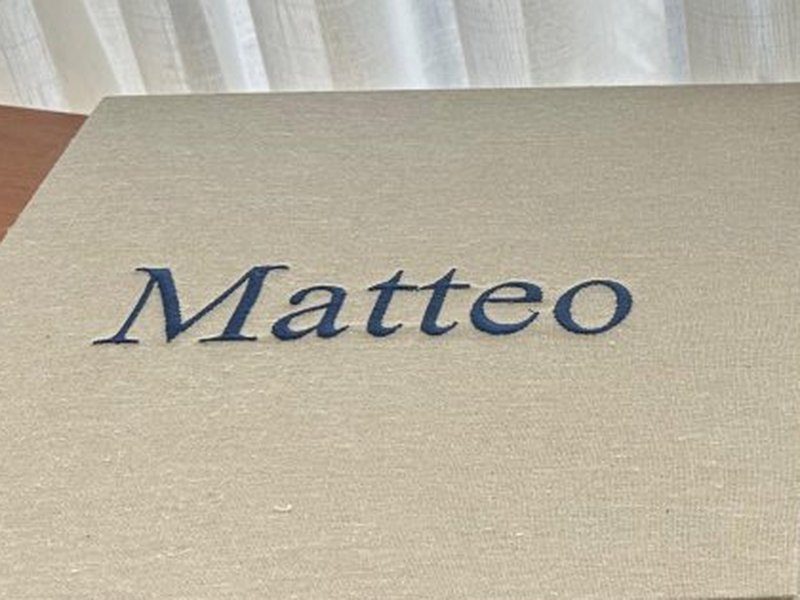 O nome Matteo aplicado em letra serifada azul na tampa fechada, sem os enfeites do bras�o