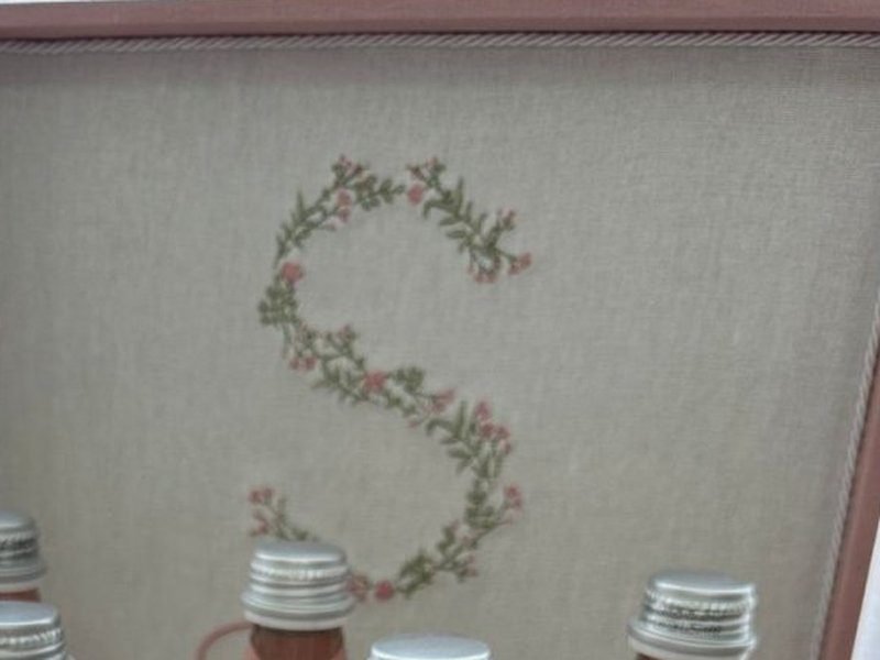 Letra S bordada na tampa da caixa, formada por ramos com flores mi�das