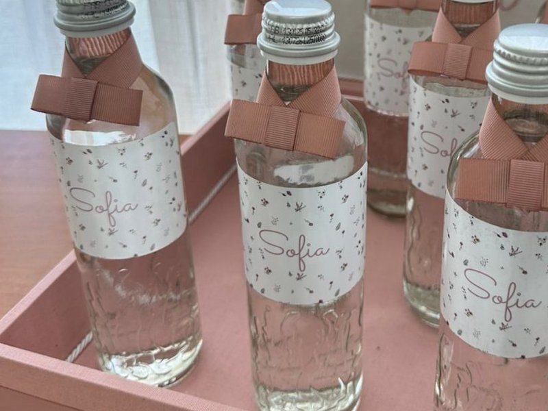 Garrafa de vidro com r�tulo floral, nome Sofia em cursiva e la�o de gorgur�o rose no gargalo