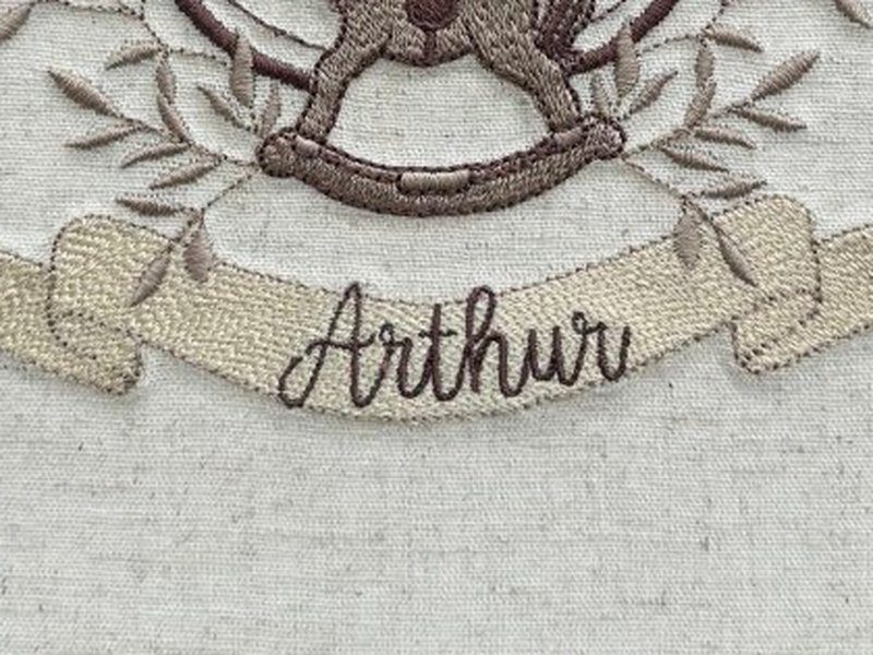 Faixa creme com o nome Arthur bordado por inteiro em cursiva marrom