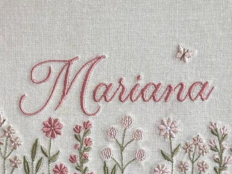 O nome Mariana bordado por inteiro em cursiva rosa, com uma borboleta � direita