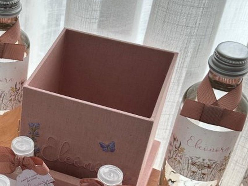 Cachep� rosa com uma borboleta lil�s bordada na lateral, ao lado das garrafas