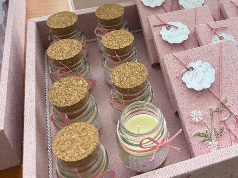 Velas em vidro com rolha de corti�a, uma aberta mostrando a cera creme, amarradas com cord�o rosa