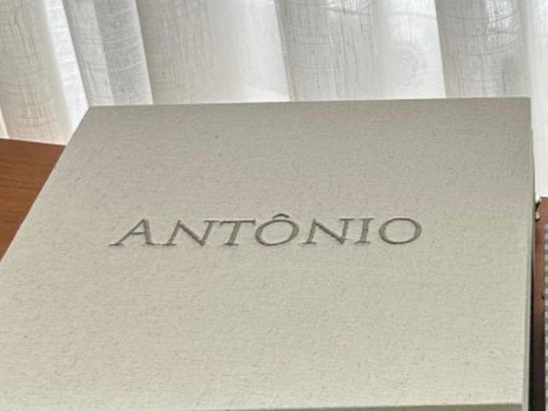 'ANTONIO' bordado por inteiro em mai�sculas tom sobre tom na tampa externa de linho cru