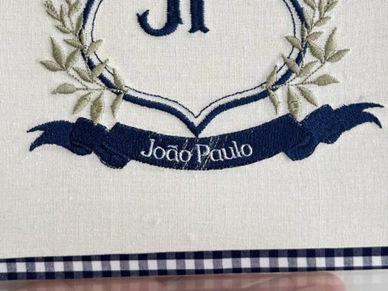 Faixa azul escuro preenchida com Jo�o Paulo bordado em letra clara vazada sobre o fundo escuro