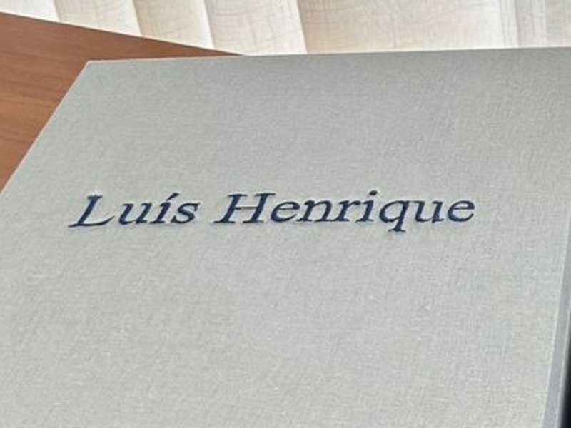 'Lu�s Henrique' bordado em azul escuro, com o acento, na tampa externa de linho cinza