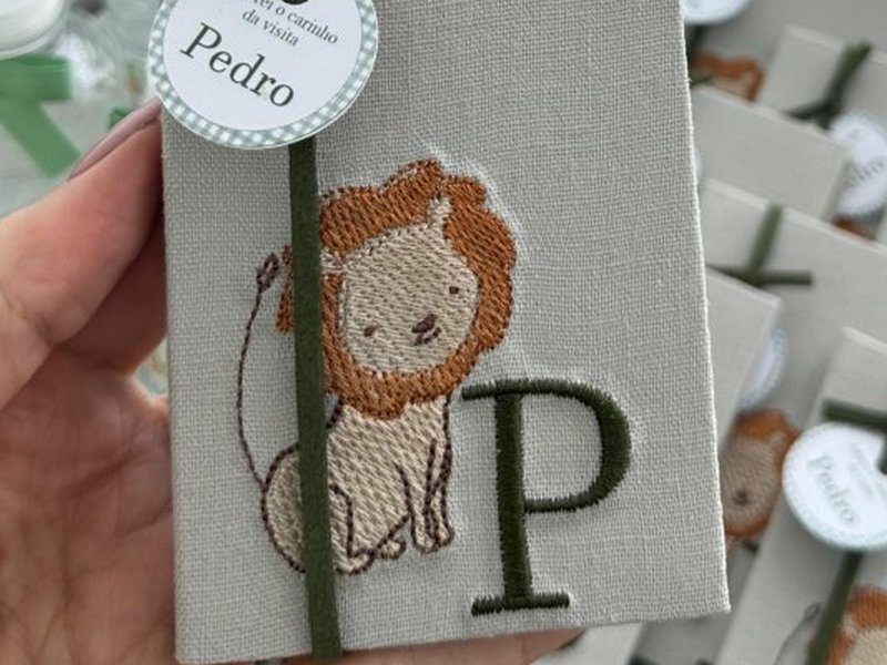 Caixinha-livro com um le�o bordado em laranja e bege ao lado da inicial P verde