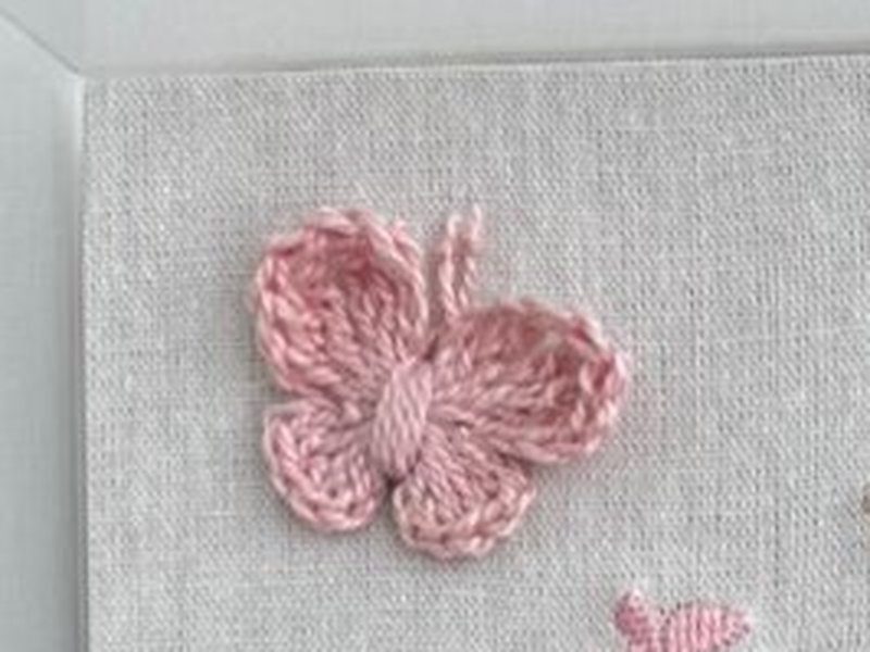 Borboleta de croch� rosa aplicada sobre o linho, com textura de ponto grosso bem diferente do bordado