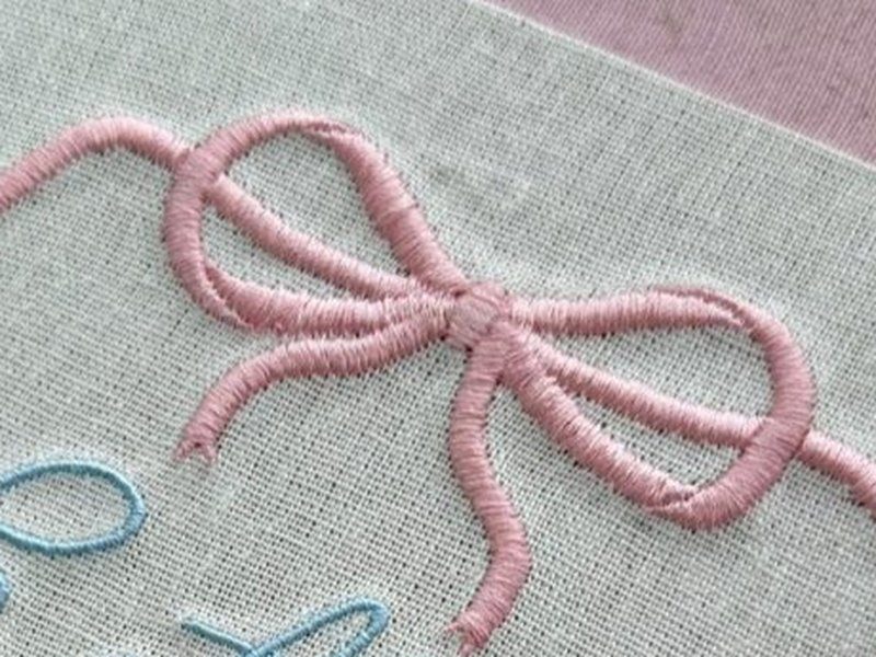 La�o rosa grande no topo, com as duas fitas descendo pelos lados e contornando a coroa