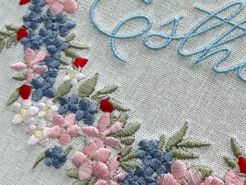 Flores azuis e rosa em ponto cheio, com frutinhas vermelhas pequenas em relevo entre as folhas