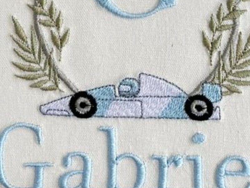Carro de corrida azul-claro bordado de perfil, com rodas pretas, na base do bras�o