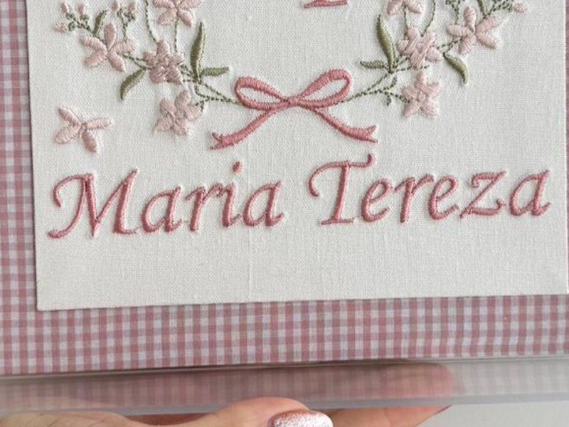 O nome Maria Tereza bordado por inteiro em letra serifada rosa, numa linha s�