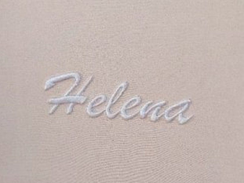 O nome Helena bordado em cursiva rose em relevo no interior da tampa, dentro da moldura de cord�o branco