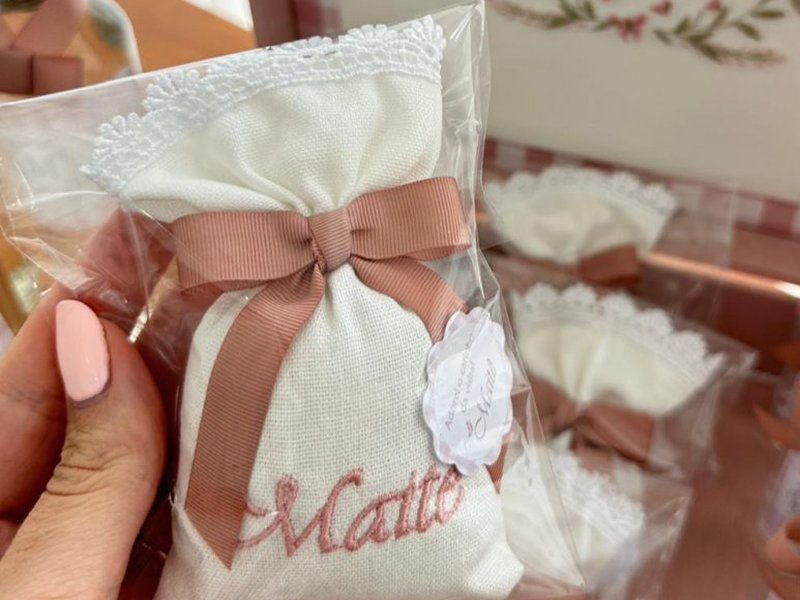 Sach� de linho cru com barrado de renda guipir, la�o rosa-velho e 'Mait�' bordado com o circunflexo