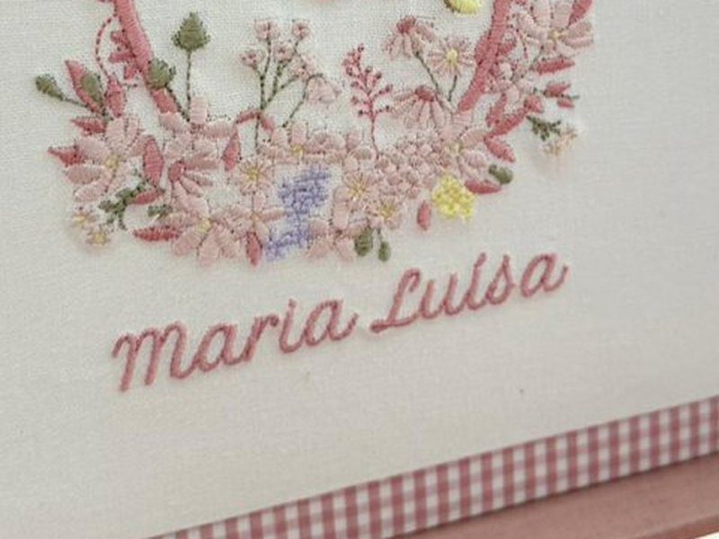 Uma borboleta amarela bordada entre as flores rosas e azuis da base da cartela