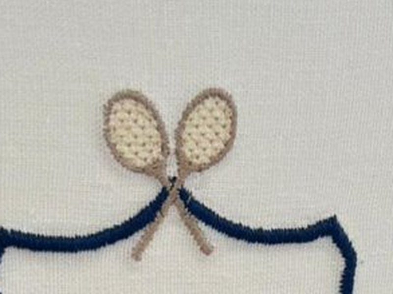 As duas raquetes de t�nis bordadas cruzadas, com as cordas marcadas ponto a ponto, acima do escudo